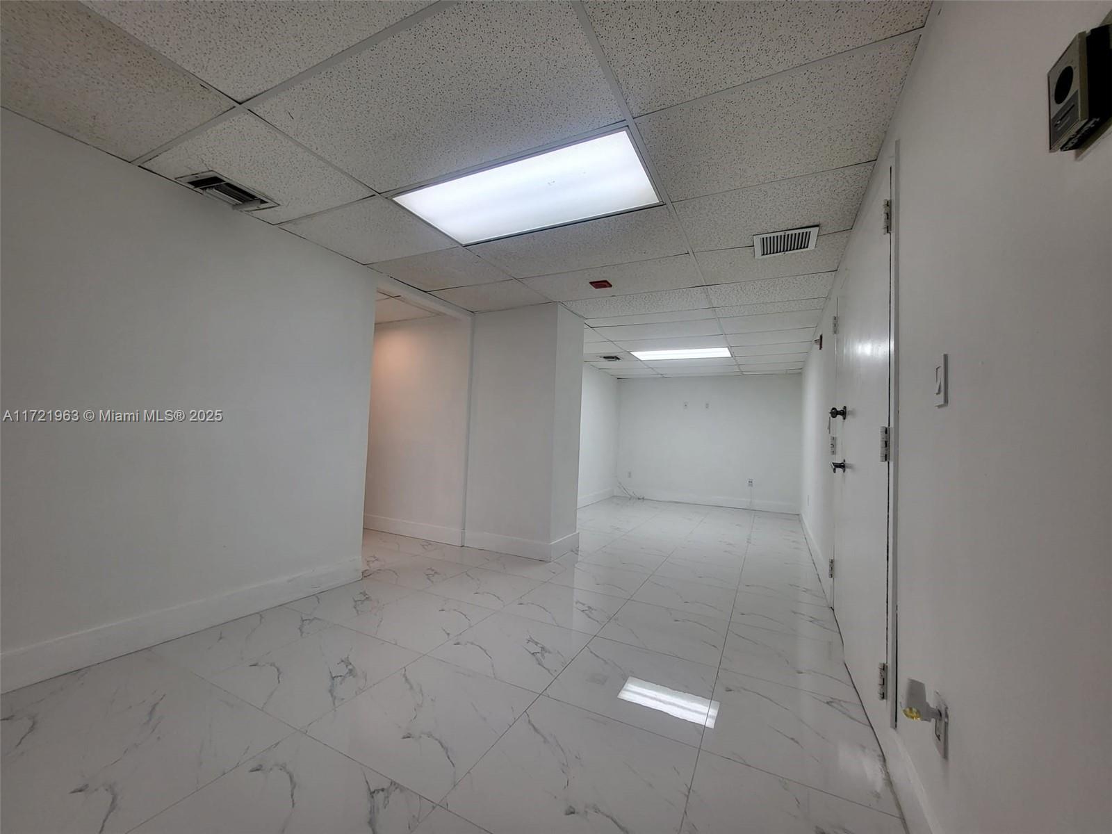 A long, narrow office space features white walls, marble-patterned tile floors, and a drop ceiling — 13499 Biscayne Blvd, North Miami FL 33181, NORTH MIAMI, FL