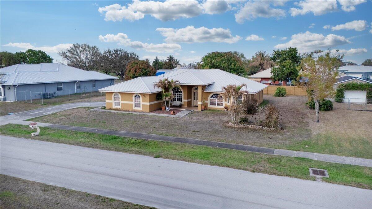 A single-story house with a tan exterior, white trim, and a metal roof — 1023 Caribbean Avenue, Clewiston FL 33440, CLEWISTON, FL