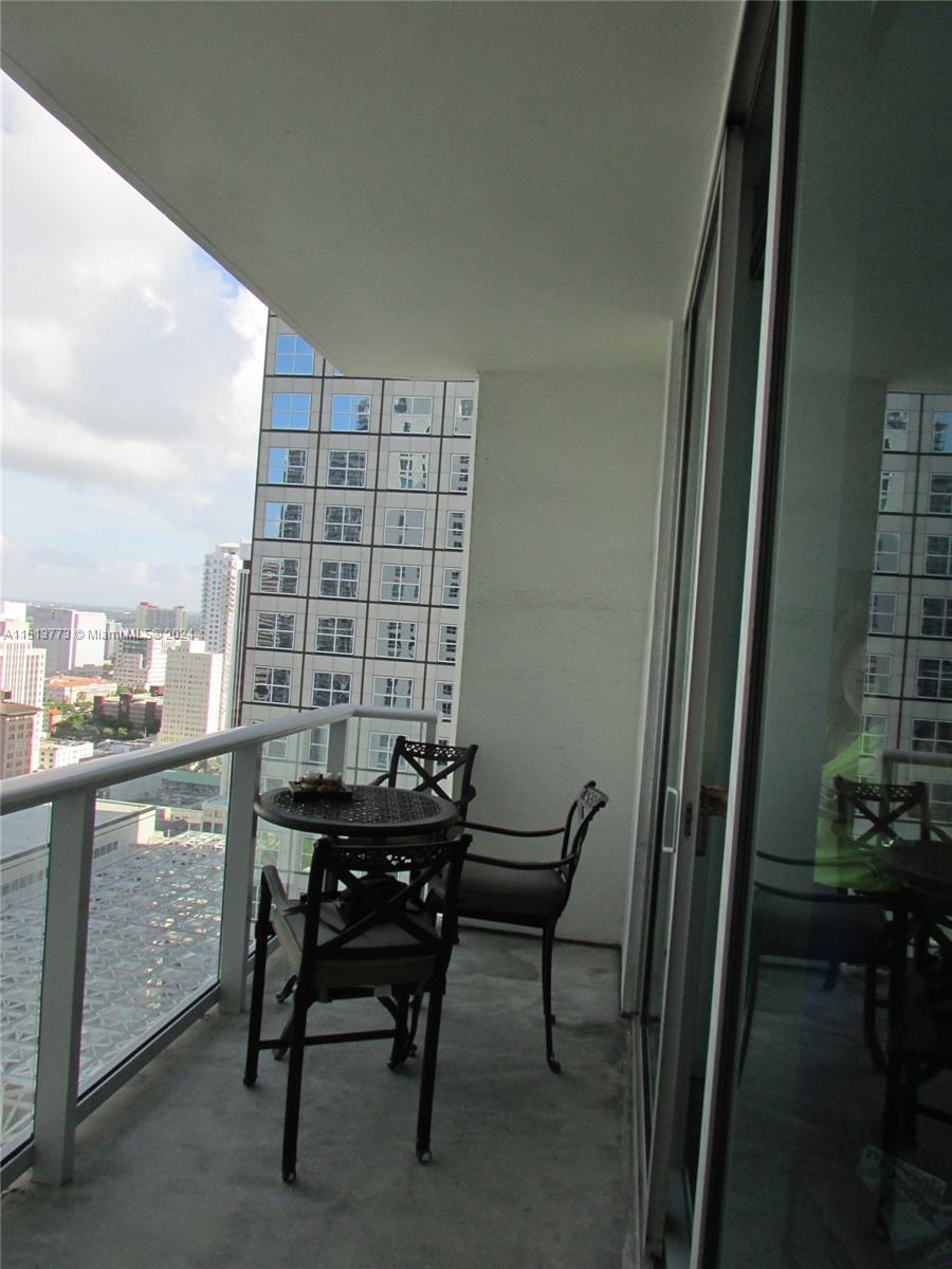 A balcony with a small table and two chairs overlooks a city skyline — 300 S Biscayne Blvd # 2709, Miami FL 33131, MIAMI, FL