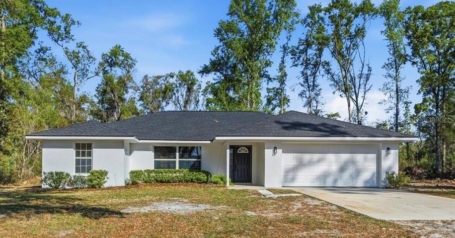 A single-story white house with a dark roof and a two-car garage sits outdoors — 957 NE 354TH AVENUE, OLD TOWN, FL