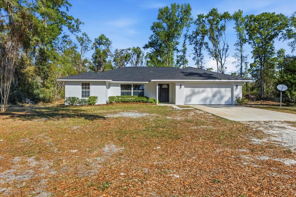 A single-story white house with a dark roof and a two-car garage — 957 NE 354TH AVENUE, OLD TOWN, FL