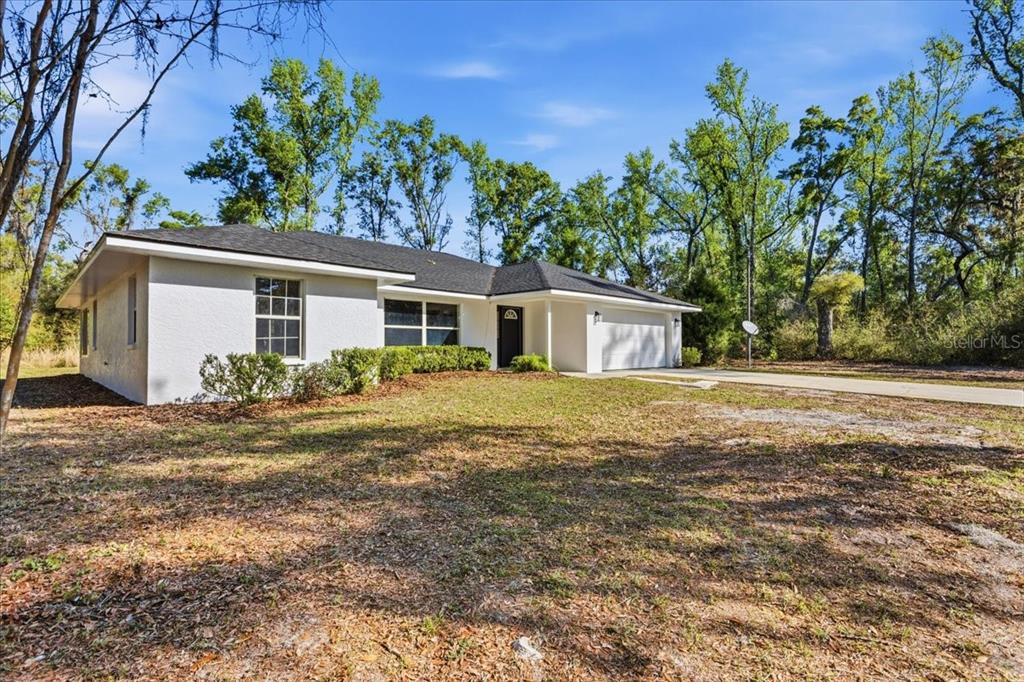 A single-story white house with a dark roof and a two-car garage — 957 NE 354TH AVENUE, OLD TOWN, FL