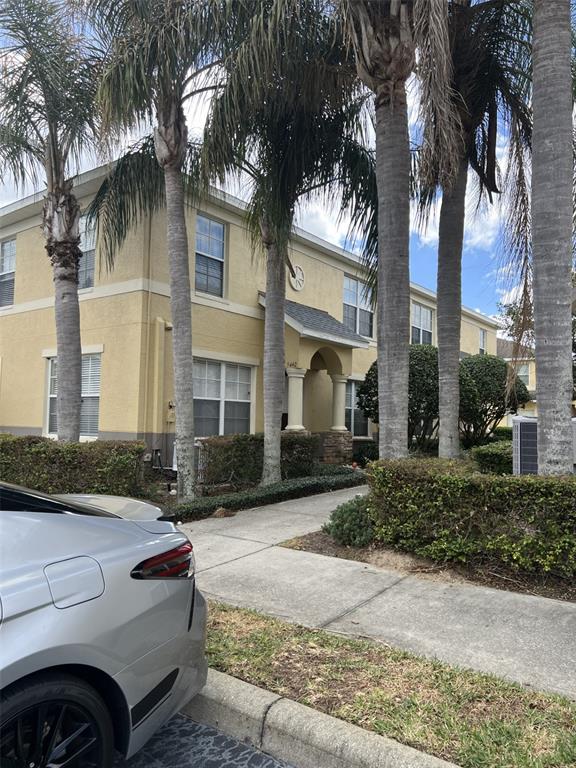 A two-story tan apartment building with palm trees and a sidewalk in the foreground — 5444 RIVER ROCK ROAD, LAKELAND, FL