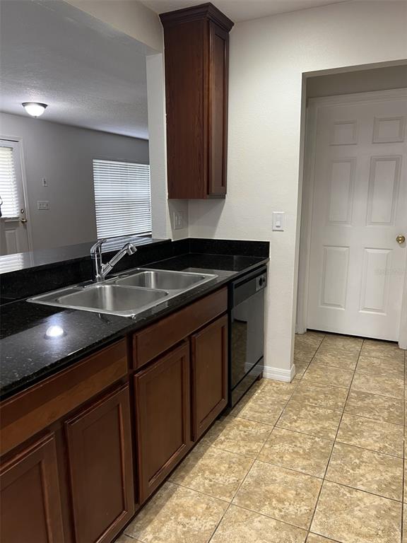 A kitchen features dark wood cabinets, black granite countertops, a stainless steel sink, and tile flooring — 5444 RIVER ROCK ROAD, LAKELAND, FL