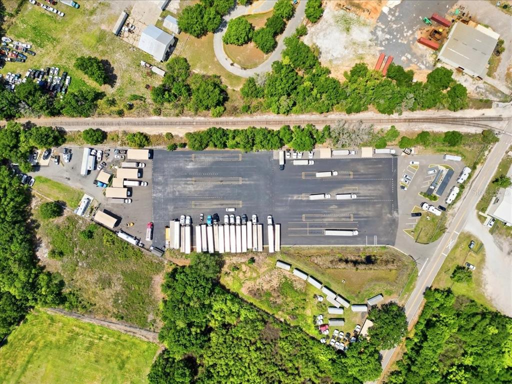Aerial view of a commercial parking lot with numerous semi-truck trailers and surrounding wooded areas — 100 S AIRPORT ROAD, LAKE WALES, FL