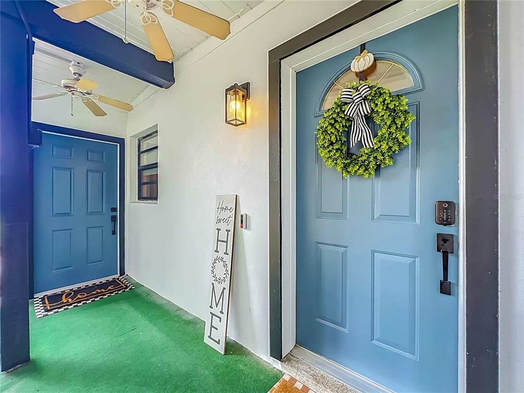 A covered porch features two blue doors, a green floor, and a decorative wreath — 719 CHEROKEE CIRCLE, SANFORD, FL