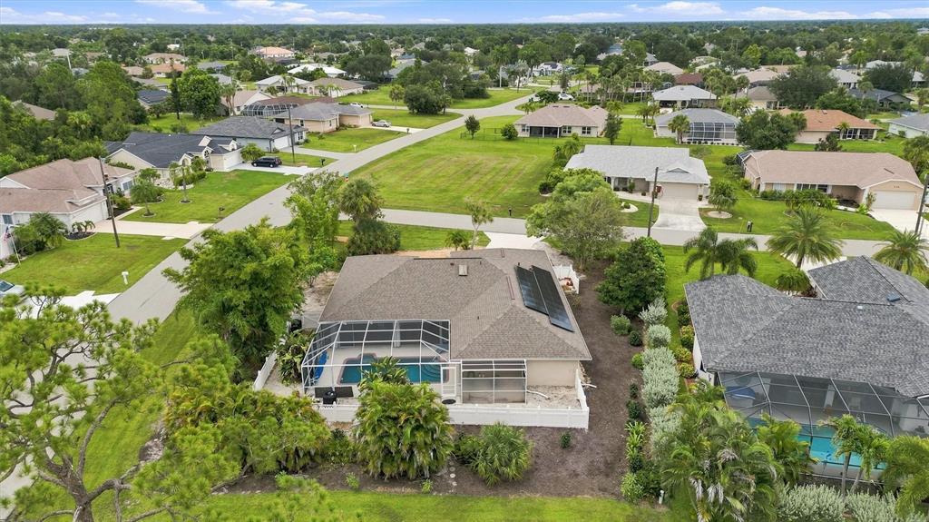 An aerial view shows a suburban house with a pool enclosure and solar roof panels — 317 SALVADOR DRIVE, PUNTA GORDA, FL
