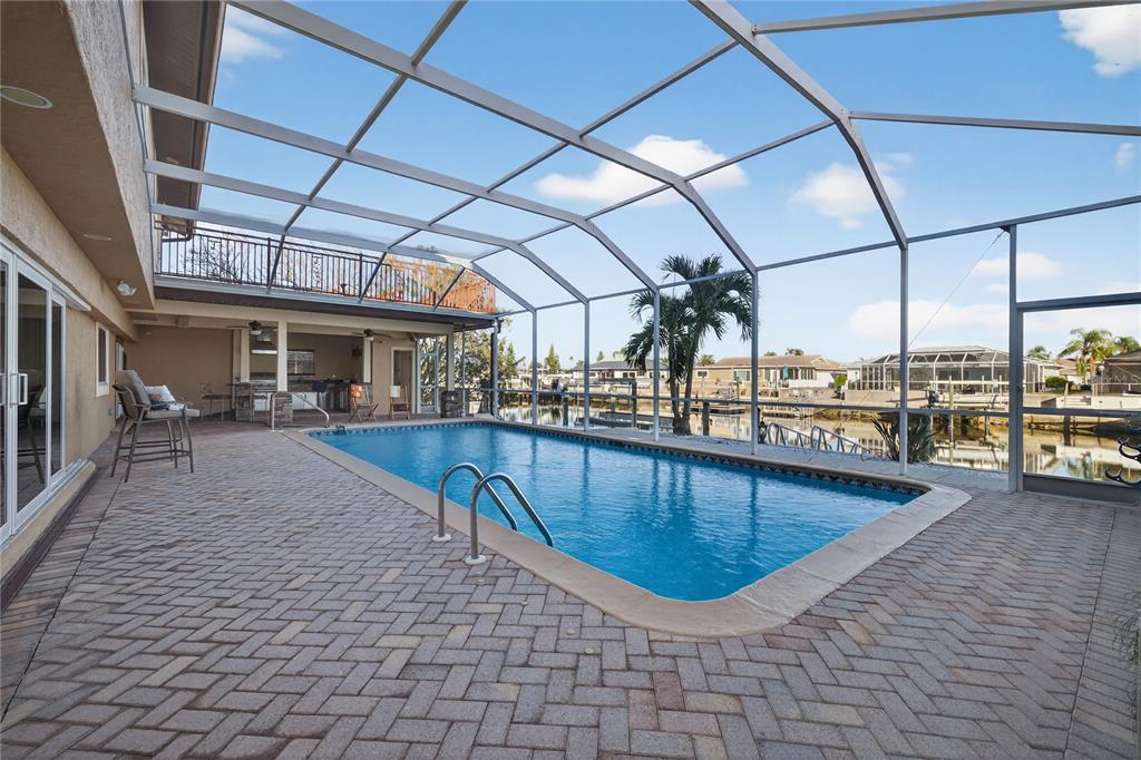 A screened-in pool patio features brick pavers, a covered outdoor kitchen, and waterfront views — 5124 SOUTH SHORE DRIVE, NEW PORT RICHEY, FL
