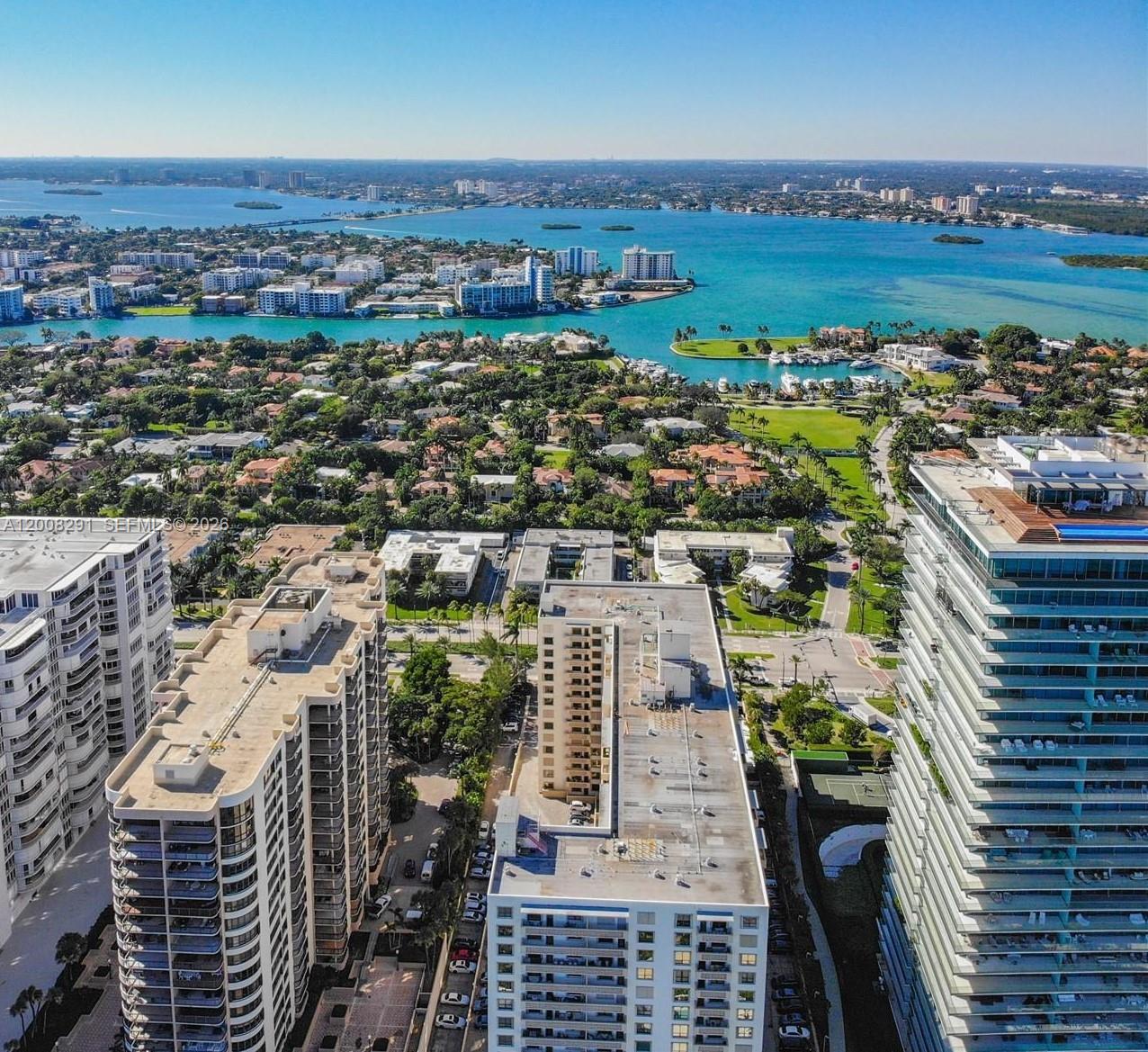 A kitchen features white cabinets, granite countertops, a stainless steel refrigerator, and a tiled backsplash — 10185 Collins # 308, Bal Harbour FL 33154, BAL HARBOUR, FL