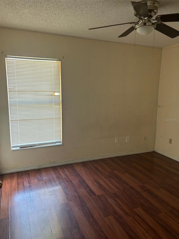 An empty bedroom features dark wood-look flooring, a ceiling fan, and a window with blinds — 673 COTULLA DRIVE, KISSIMMEE, FL