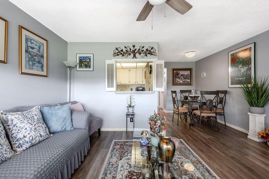A living room and dining area with gray walls, wood-look flooring, and a kitchen pass-through — 393 Windsor, West Palm Beach FL 33417, WEST PALM BEACH, FL