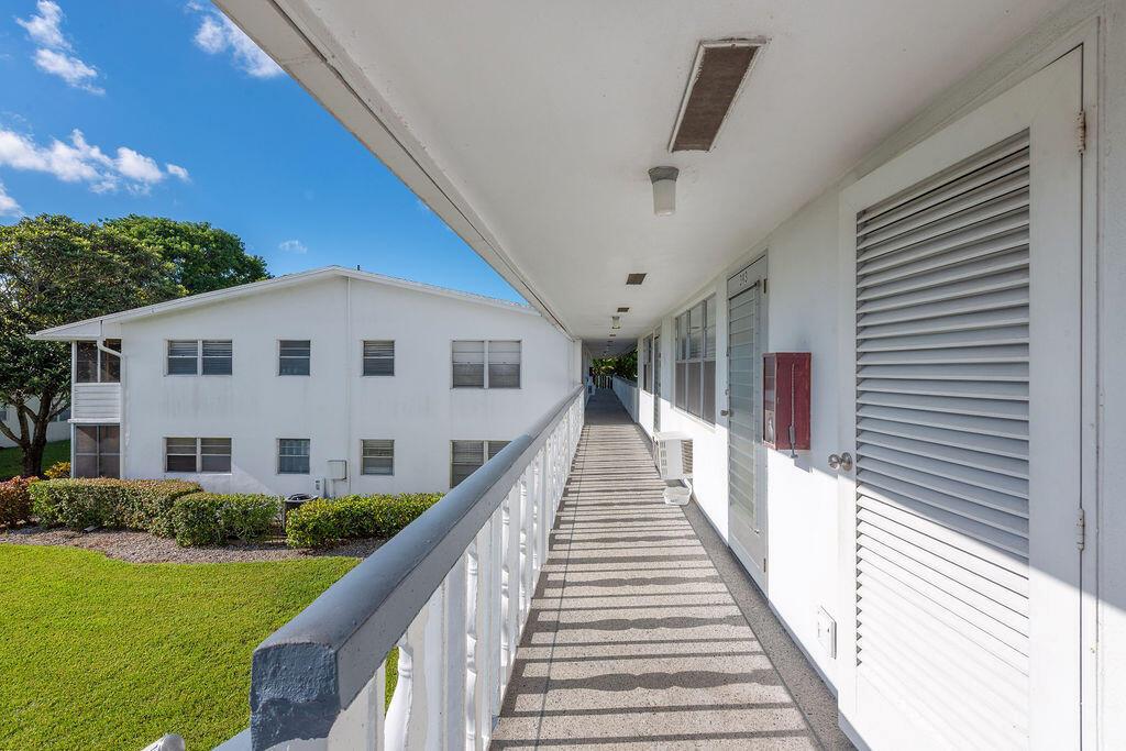 An outdoor walkway with white railings overlooks a grassy lawn and a neighboring apartment building — 393 Windsor, West Palm Beach FL 33417, WEST PALM BEACH, FL