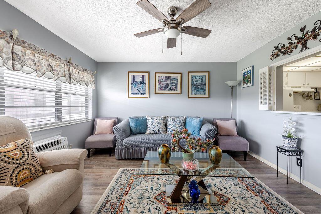 A living room with a grey sofa, patterned rug, glass coffee table, and ceiling fan — 393 Windsor, West Palm Beach FL 33417, WEST PALM BEACH, FL