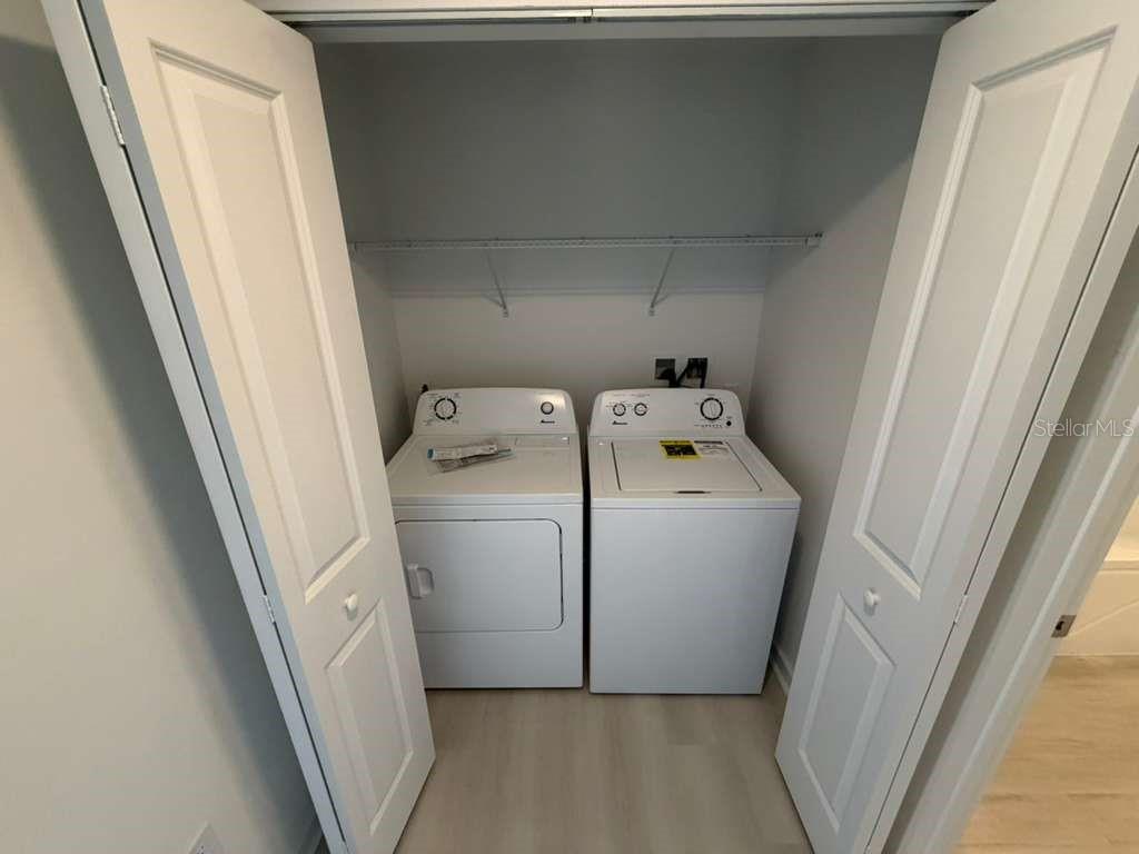 A laundry closet contains a white top-loading washing machine and a matching dryer — 5587 MILLENIA PARK BOULEVARD UNIT 502, ORLANDO, FL