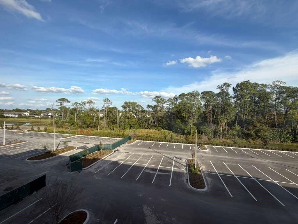 An elevated view of a paved parking lot bordered by trees and a blue sky — 5587 MILLENIA PARK BOULEVARD UNIT 502, ORLANDO, FL