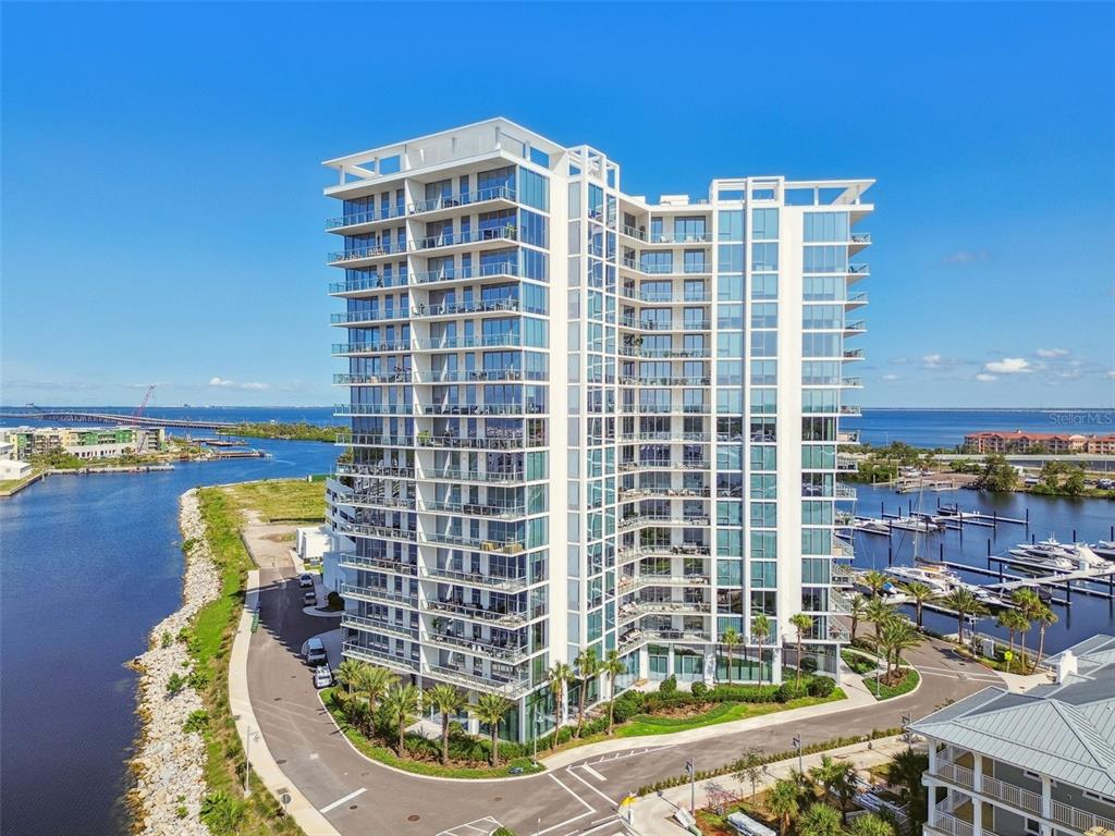 An aerial view of a modern high-rise apartment building situated on a waterfront peninsula — 5120 MARINA WAY UNIT 15005, TAMPA, FL