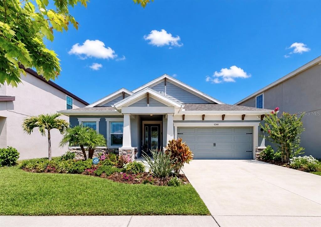 A single-story suburban house with a gray garage, front porch, and landscaped yard — 6364 ROADSTEAD COURT, APOLLO BEACH, FL