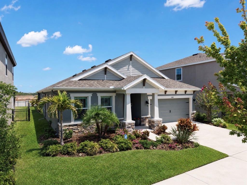 A single-story house with gray siding, a stone base, and a two-car garage — 6364 ROADSTEAD COURT, APOLLO BEACH, FL