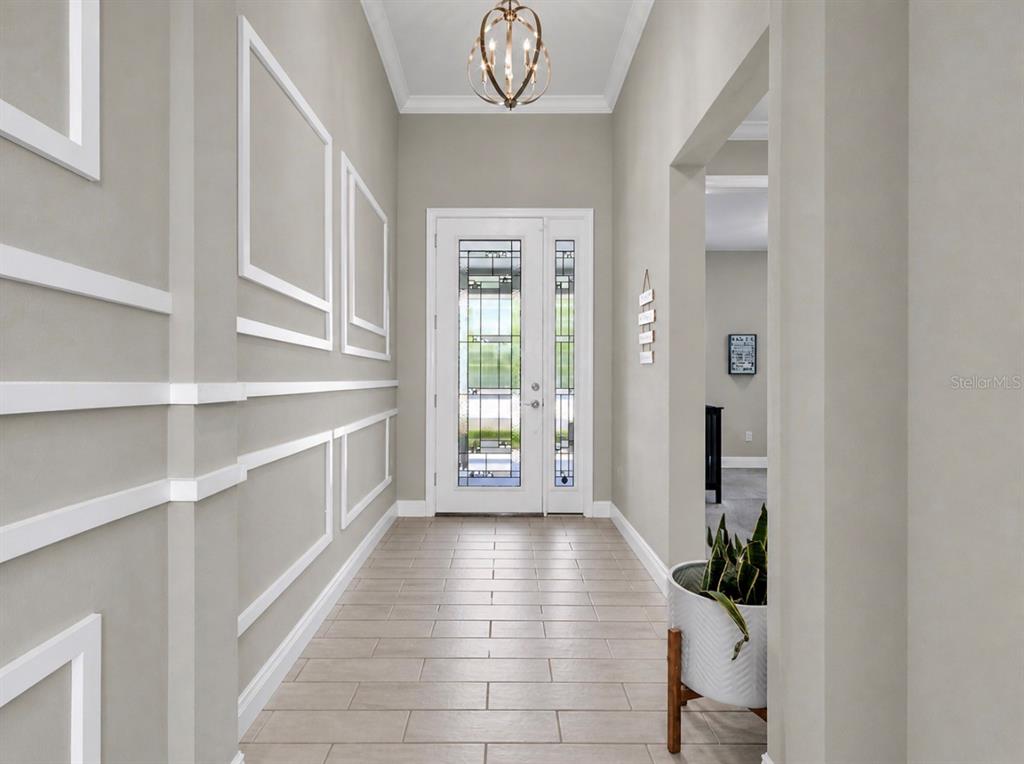 A foyer with tile flooring, wall molding, a glass-paneled front door, and a hanging light — 6364 ROADSTEAD COURT, APOLLO BEACH, FL