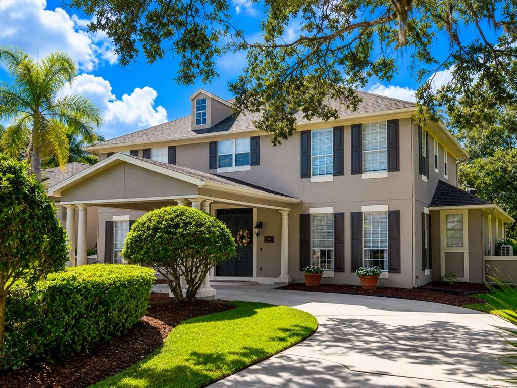 A two-story house with a gray exterior, dark shutters, and a palm tree in front — 3909 CASSIA DRIVE, ORLANDO, FL