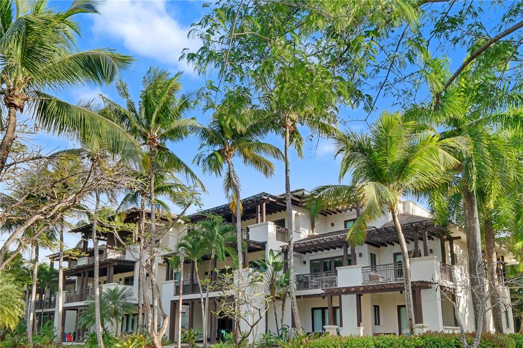 A multi-story tropical resort building features white stucco walls, dark wood pergolas, and palm trees — 7000 Bahia Beach Boulvard LAS VENTANAS I UNIT 222, RIO GRANDE, PR
