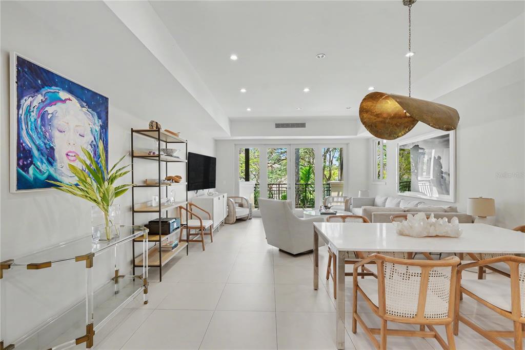 A bright, open-concept living and dining area features white tile floors and large glass doors — 7000 Bahia Beach Boulvard LAS VENTANAS I UNIT 222, RIO GRANDE, PR