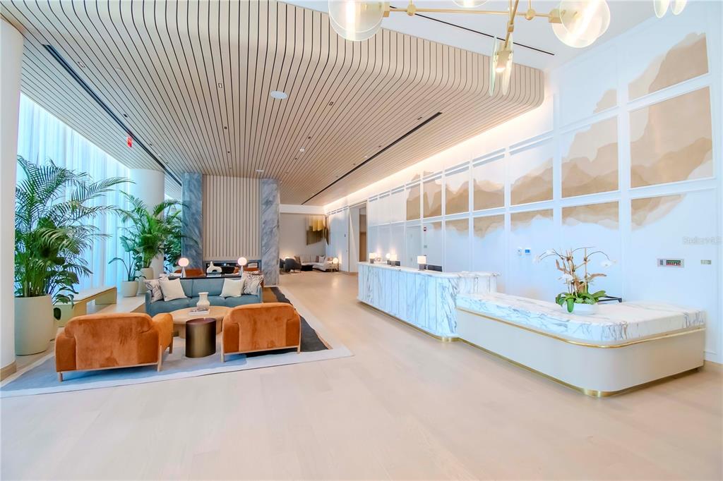 A modern hotel lobby features a marble reception desk, lounge seating, and slatted wood ceilings — 3101 W BAYSHORE BOULEVARD UNIT 804, TAMPA, FL