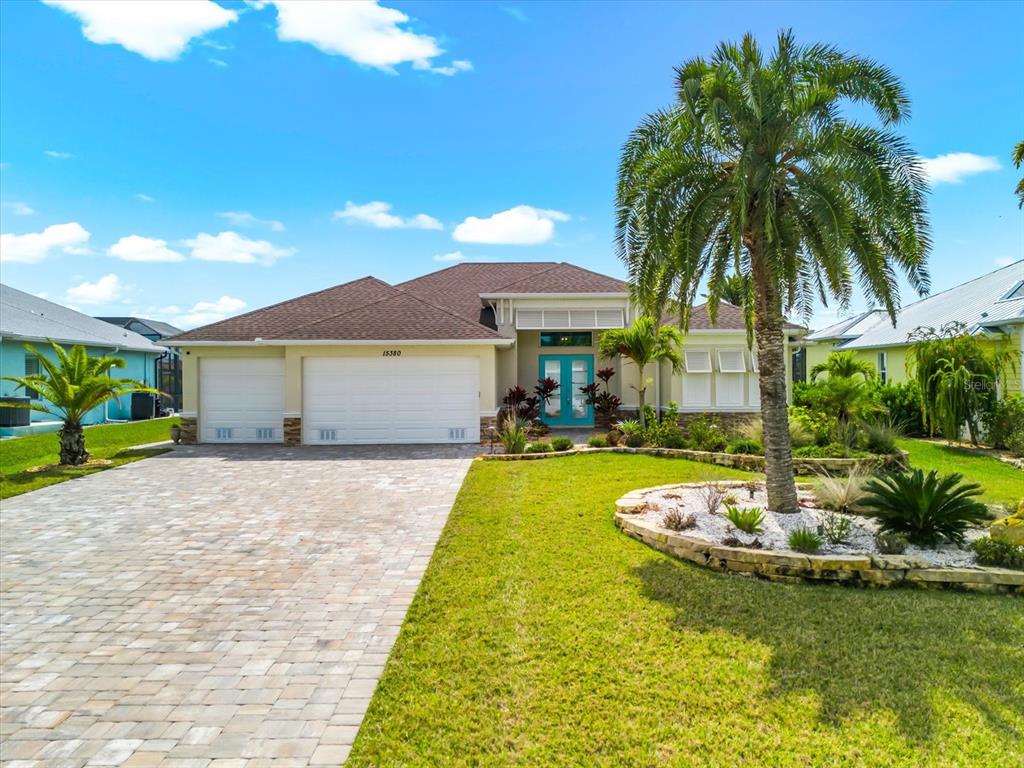 A single-story house with a paved driveway, a three-car garage, and a palm tree — 15380 ALSASK CIRCLE, PORT CHARLOTTE, FL