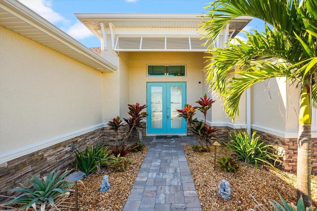 A paved walkway leads to the bright blue double front doors of a stucco home — 15380 ALSASK CIRCLE, PORT CHARLOTTE, FL