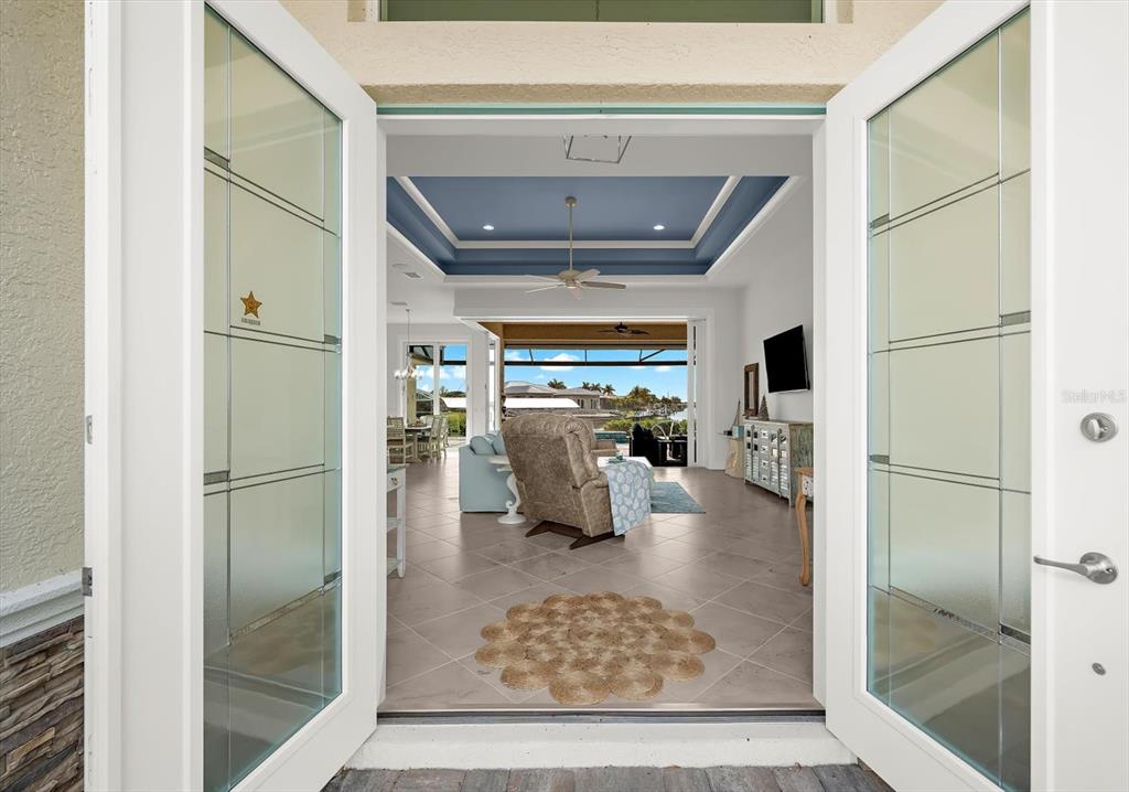 A view through open double glass doors into a living room with a tray ceiling — 15380 ALSASK CIRCLE, PORT CHARLOTTE, FL