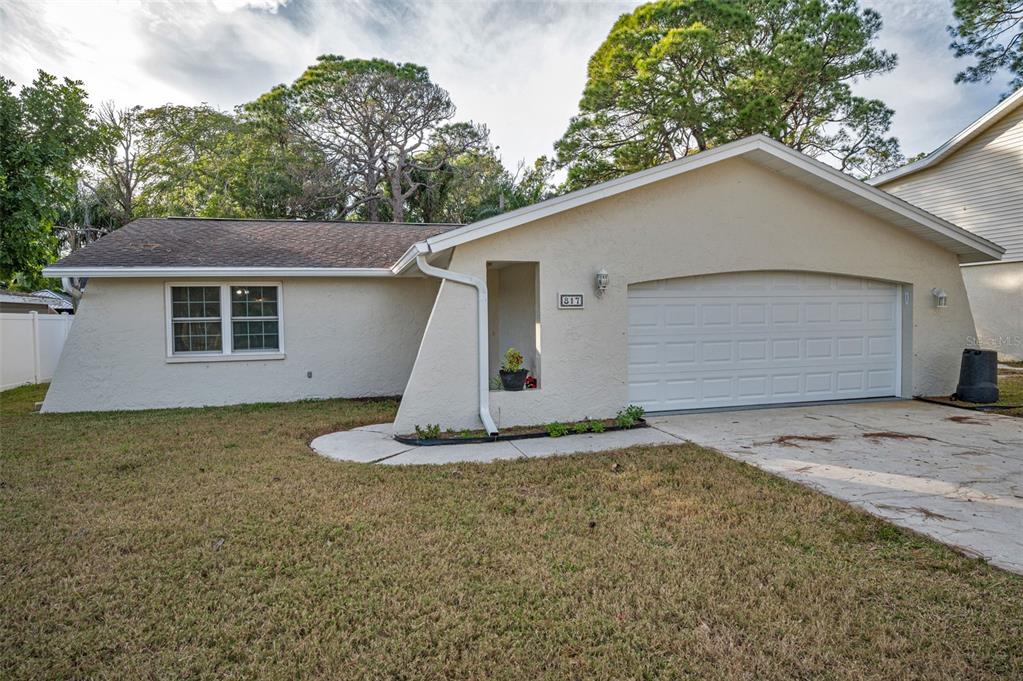 A single-story house with a beige stucco exterior, a two-car garage, and a front lawn — 817 RIVERSIDE DRIVE, TARPON SPRINGS, FL