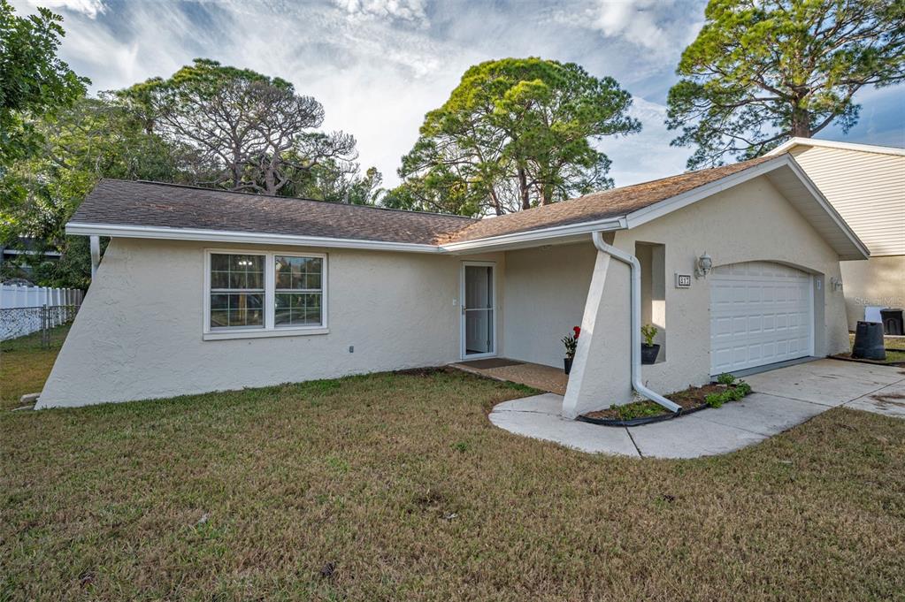 A single-story house with a beige stucco exterior, a shingled roof, and an attached garage — 817 RIVERSIDE DRIVE, TARPON SPRINGS, FL