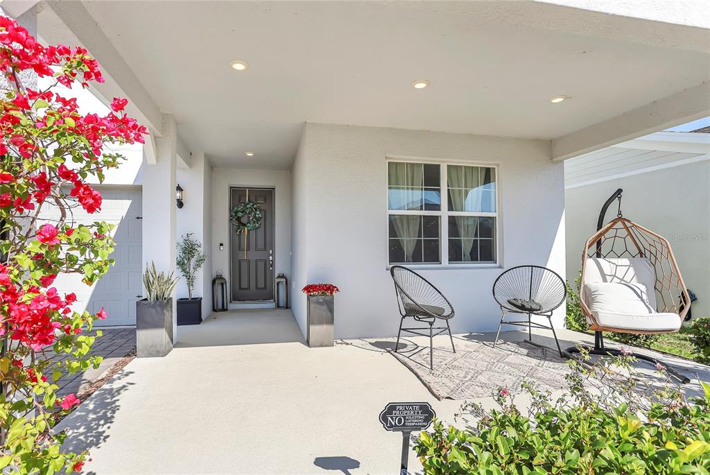 A covered front porch features a dark door, two metal chairs, and a hanging chair — 18907 RAWSON STREET, ORLANDO, FL