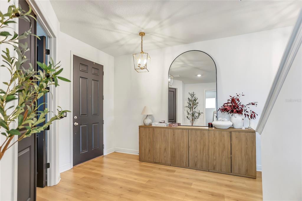 A bright entryway features light wood flooring, a dark door, and a modern console table — 18907 RAWSON STREET, ORLANDO, FL