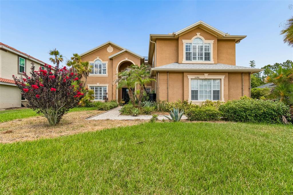 A two-story tan stucco house with a paved walkway and a front lawn — 10746 CORY LAKE DRIVE, TAMPA, FL