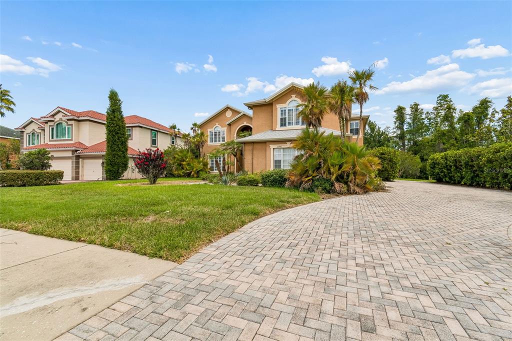 A two-story tan stucco house with a paved driveway and palm trees in the front yard — 10746 CORY LAKE DRIVE, TAMPA, FL
