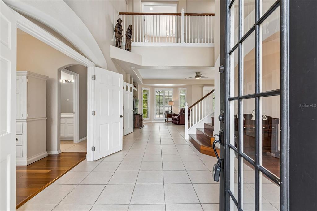 A bright entryway features light tile floors, a wooden staircase, and a second-floor balcony — 10746 CORY LAKE DRIVE, TAMPA, FL