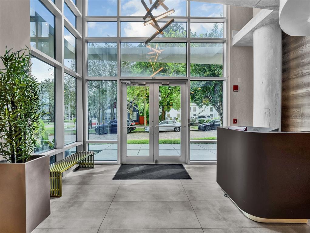 A modern building lobby features floor-to-ceiling windows, a reception desk, and a metal bench — 525 E JACKSON STREET UNIT P3, ORLANDO, FL