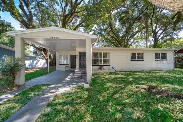 A single-story house with a large carport and white siding sits under mature trees — 3613 AMIGOS AVENUE, ORLANDO, FL