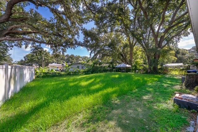 A grassy backyard features large oak trees, a white vinyl fence, and a small canopy — 3613 AMIGOS AVENUE, ORLANDO, FL