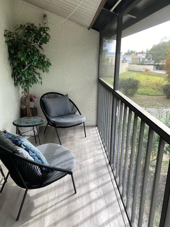 A screened-in balcony features two gray chairs, a small glass table, and a potted plant — 2377 LAKE HEATHER HEIGHTS COURT UNIT 2377, DUNEDIN, FL