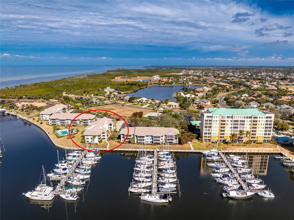 An aerial view shows a multi-story residential building circled in red beside a boat marina — 3245 SUGARLOAF KEY ROAD UNIT 24C, PUNTA GORDA, FL
