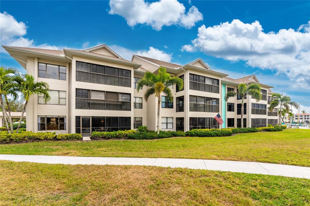 A multi-story apartment building with screened balconies and palm trees on a grassy lawn — 3245 SUGARLOAF KEY ROAD UNIT 24C, PUNTA GORDA, FL