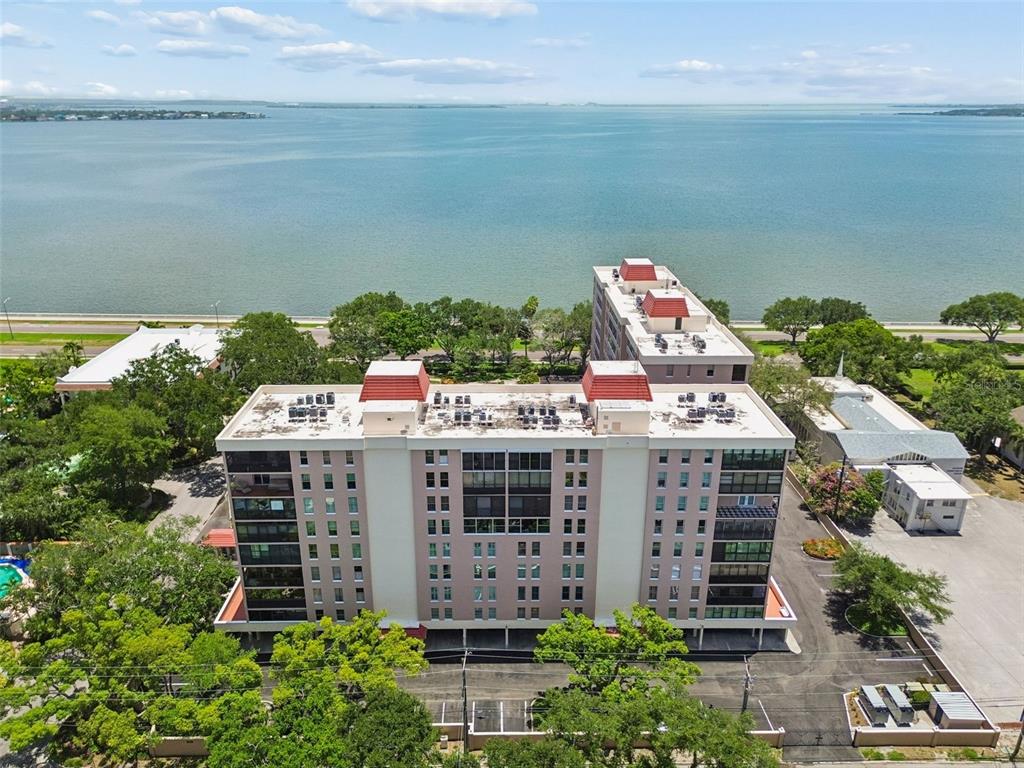An aerial view shows a multi-story apartment building with a red-tiled roof near water — 2403 S ARDSON PLACE UNIT 902B, TAMPA, FL