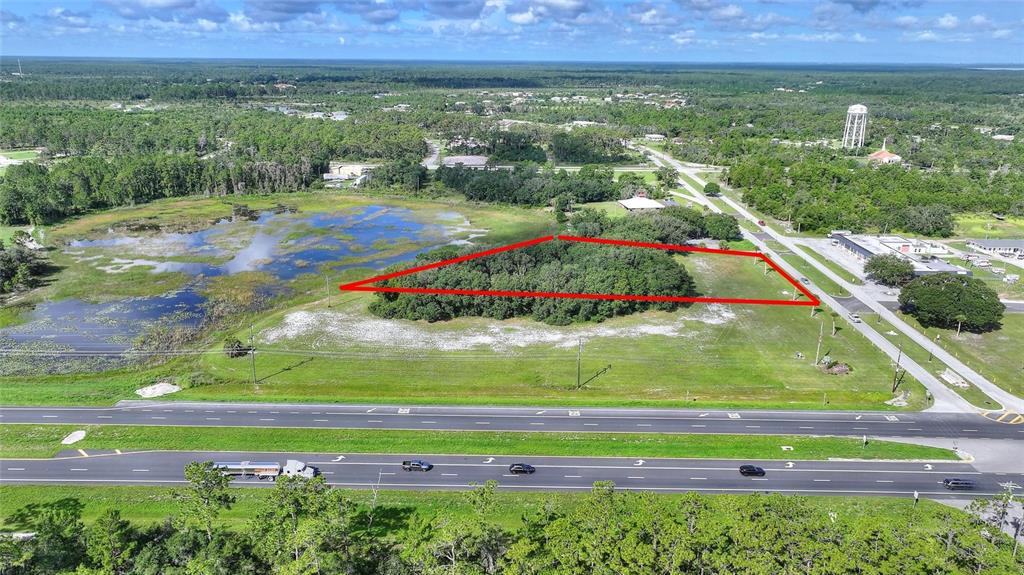 An aerial view shows a triangular wooded lot bordered by a highway and a wetland — DELAND AVENUE, INDIAN LAKE ESTATES, FL