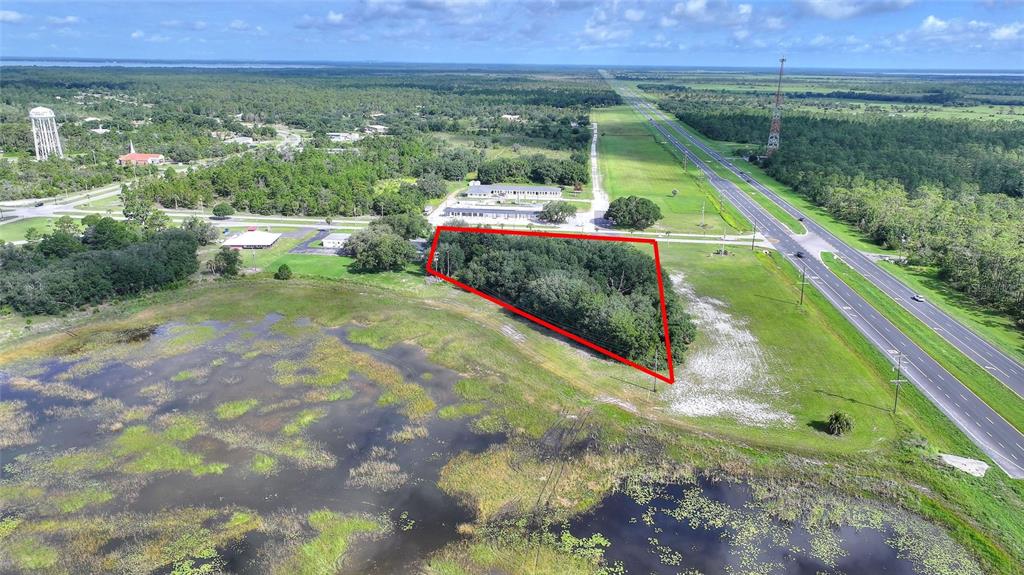 An aerial view shows a wooded, triangular plot of land bordered by a highway and wetlands — DELAND AVENUE, INDIAN LAKE ESTATES, FL