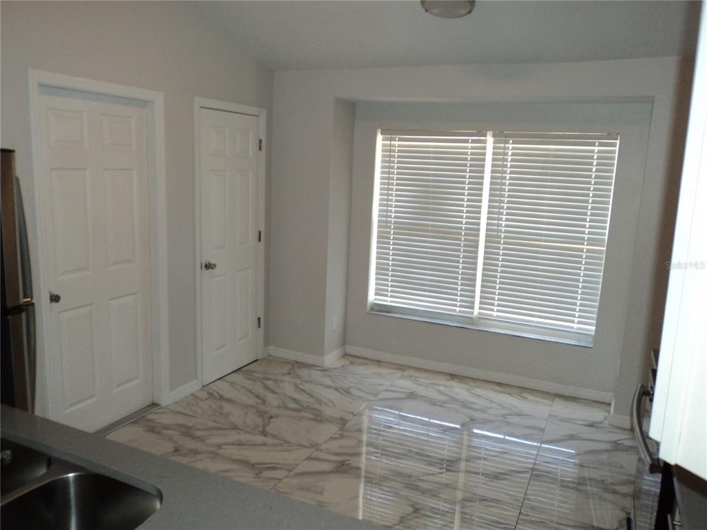A kitchen area features light gray walls, white doors, and large marble-patterned floor tiles — 548 E MONTROSE STREET, CLERMONT, FL