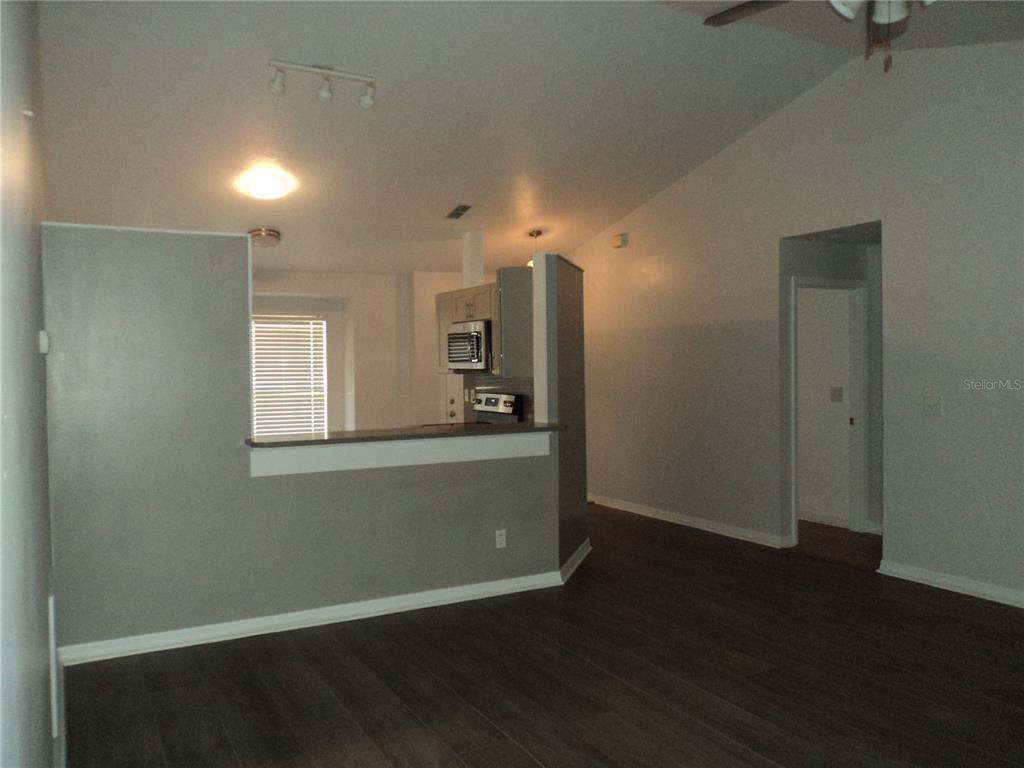 A living area with dark wood-look flooring opens to a kitchen with a breakfast bar — 548 E MONTROSE STREET, CLERMONT, FL