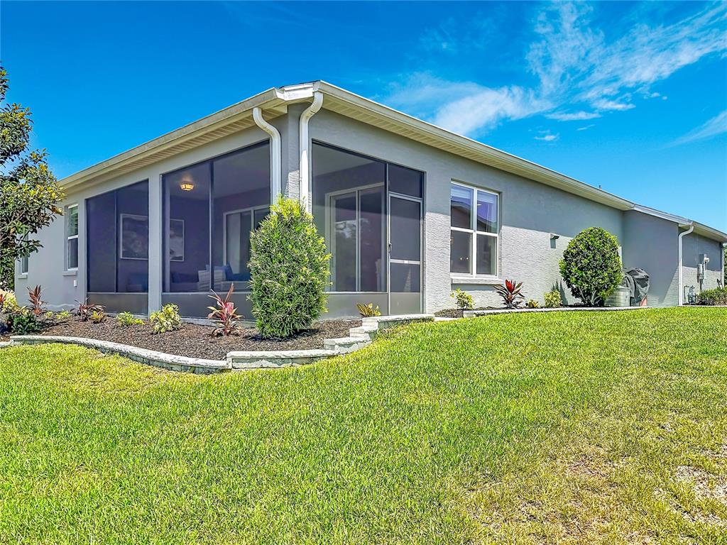 The exterior of a house features a screened-in patio, a lawn, and landscaped garden beds — 4240 JAMES RIVER CIRCLE, LEESBURG, FL