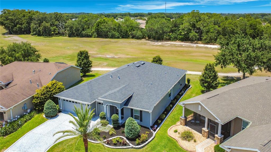 An aerial view shows a gray house with a shingled roof and landscaped front yard — 4240 JAMES RIVER CIRCLE, LEESBURG, FL